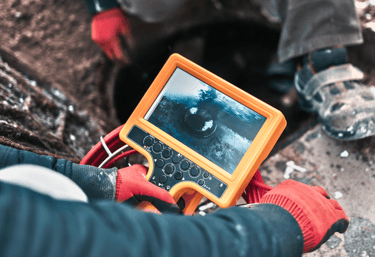 A photo of a home inspector using a sewer scope camera to inspect a properties sewer lines.