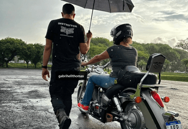 Instrutor segurando guarda chuva para pilota em moto