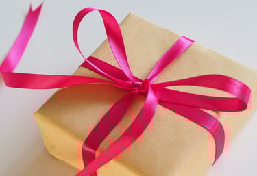 brown gift box with a bright pink bow