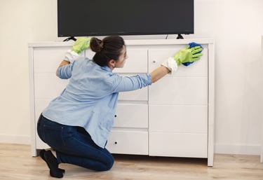 a woman cleaning a dresser with gloves