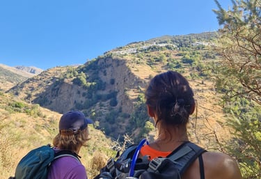 two people standing on a mountain top with backpacks