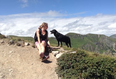 Une femme, éducateur canin, assise en haut d'une montagne avec son chien