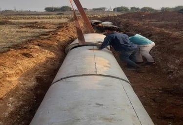 two people standing in a field with a large pipe pipe