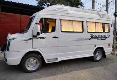 White Tempo Traveller van for rent in Chennai, parked near a red building.