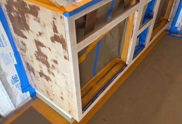 Sanded kitchen cabinets prepared for painting with 3M masking film and blue painter's tape.