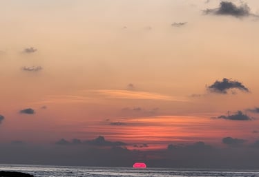 a sunset with a sailboat in the water