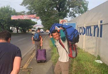 Roger smiling holding luggage over shoulders.