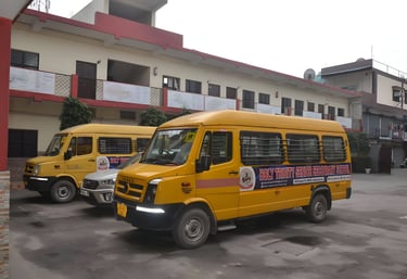 Yellow school buses parked at Holy Trinity Senior Secondary School campus building.