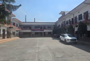 Two-story white school building with a large open paved courtyard