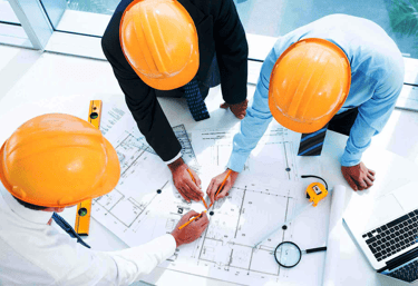 Imagem ilustrativa de três engenheiros visto por cima trabalhando