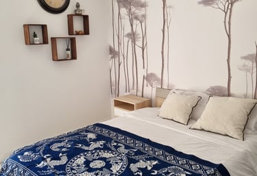 a bed with a blue blanket and a clock on the wall