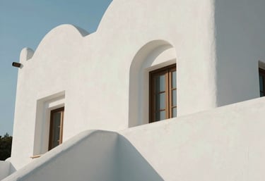 Clean, luminous architectural detail of a Mediterranean-style building with soft white curves and natural light, Spanish-speaking region context, serene and minimalist.