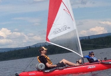 a man and a woman are sitting in a kayak with a sail
