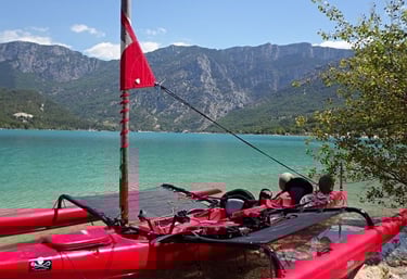 a red kayak is sitting on a rocky shore