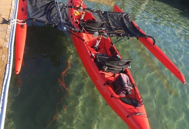 a red kayak is sitting on the water hooked to a platoon