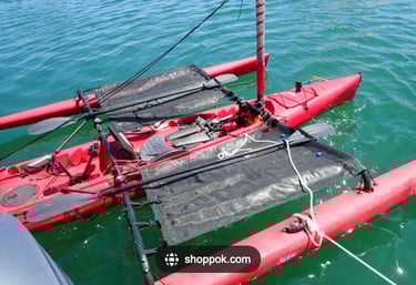 a red kayak with two outriggers with black trampolines