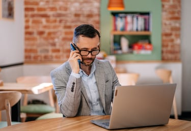 Tomasz Majdosz, man talking on the mobile phone while looking at his laptop