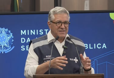 a man in a vest and glasses speaking into a microphone