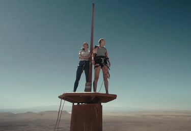 two people standing on top of a pole with a pole