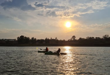 Madre e hija remando sobre aguas tranquilas en la presa de la Vega rodeadas de naturaleza