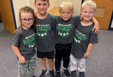 four young children standing in a hallway with their arms around each other
