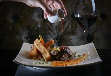 Gourmet Steak Dinner – Steak with sauce, fries, and red wine.