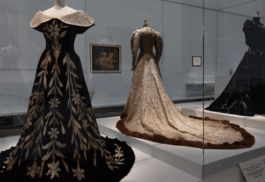 Historic couture gowns on display at fashion museum exhibit.