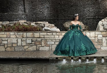 a woman in a green quinceanera dress standing in front of a waterfall