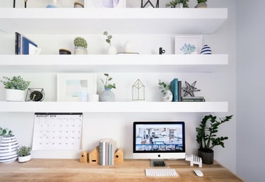 Minimalist home office with wooden desk, floating shelves, plants, and computer