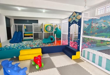 Indoor kids play area featuring a large ball pit, slides, and colorful soft play equipment.