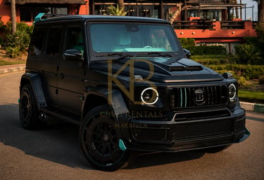 Matte black Brabus G-Wagon luxury SUV rental parked in front of a tropical resort in Marbella.