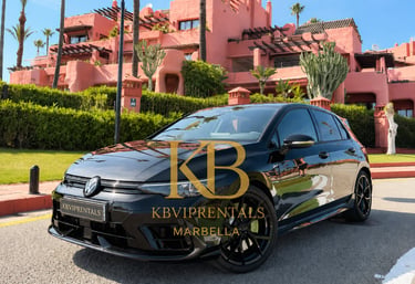 Black Volkswagen Golf R rental car parked in front of a luxury pink resort in Marbella.