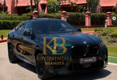 A black BMW X6 luxury SUV for rent parked in front of a pink Mediterranean villa in Marbella.