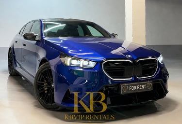 Luxury blue BMW M5 sedan for rent in Marbella featuring black rims and sleek design.