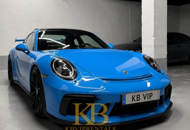 A vibrant blue Porsche 911 GT3 luxury sports car parked in a Marbella rental garage.