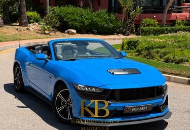 Blue Ford Mustang convertible sports car for rent on a sunny road in Marbella.