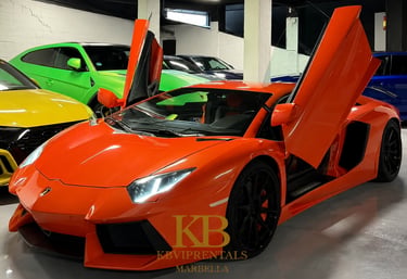 Orange Lamborghini Aventador with scissor doors open in a luxury car rental showroom.
