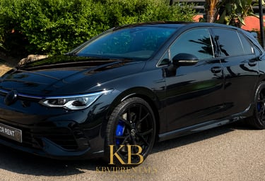 Sleek black Volkswagen Golf R hatchback rental car parked on a sunny street with blue brake calipers.