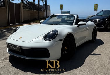 White Porsche 911 Carrera convertible luxury rental car parked on a sunny street in Marbella.
