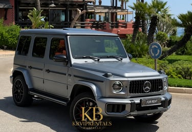 Matte grey Mercedes-Benz G-Class luxury SUV for rent parked in a sunny tropical location.