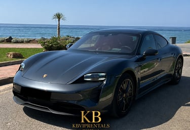Luxury grey Porsche Taycan electric car parked by the Mediterranean Sea in Marbella.