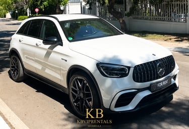 White Mercedes-Benz AMG luxury SUV for rent parked on a sunny street in Marbella.