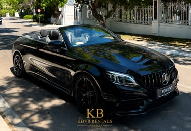 Black Mercedes AMG convertible luxury car rental parked on a sunny street in Marbella.