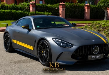 Matte grey Mercedes-AMG GT luxury sports car with yellow racing stripes parked outdoors for rent.