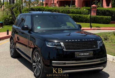 Luxury black Range Rover SUV for rent parked outside a tropical resort in Marbella.