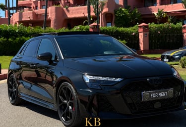 Black Audi RS3 hatchback rental parked in front of a luxury pink resort in Marbella.