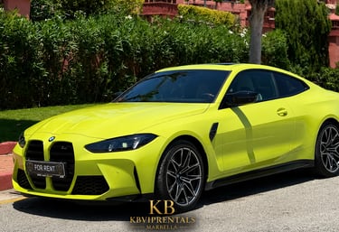 Yellow BMW M4 luxury sports car for rent in Marbella, parked on a sunny street near green hedges.