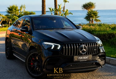 Black Mercedes-AMG GLE 63 S Coupe luxury car rental parked by the ocean in Marbella.