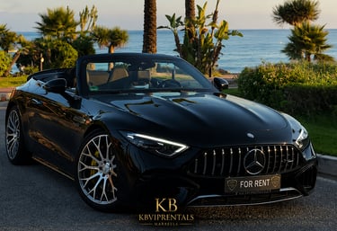 Black Mercedes-AMG SL convertible luxury car rental parked by the ocean at sunset in Marbella.
