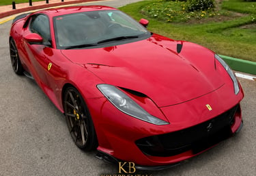 Red Ferrari 812 Superfast luxury sports car parked on a paved road in Marbella.